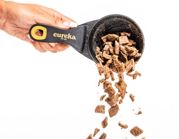Hand pouring Eureka dog food from a scoop, aligning with the blog's guidance on dog food choices.