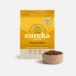 Bag of Eureka Pet Co Turkey & Duck air-dried dog food beside a tan bowl filled with the food.
