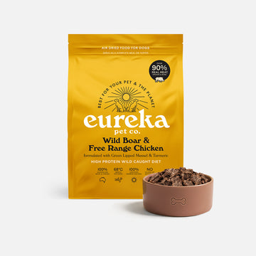 Bag of Eureka Pet Co Wild Boar & Free Range Chicken air-dried dog food beside a terracotta bowl filled with the food.