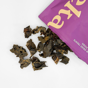 Eureka Pet Co. Rockin' Roo Trail Mix natural air-dried dog treats spilling from a purple bag onto a white surface showing rich dark textured pieces